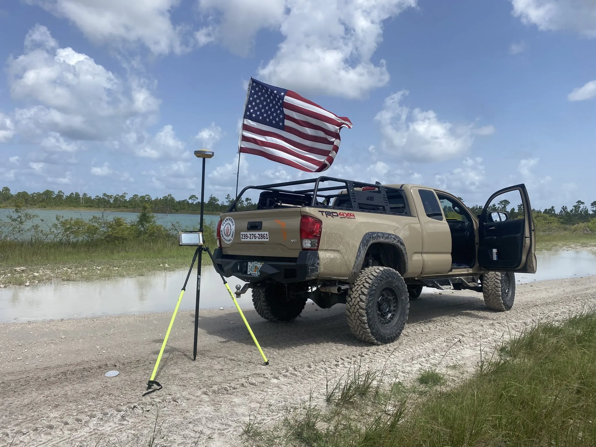 Plan Right Survey's truck flying an American flag beside a GPS survey rover on a Southwest Florida job site